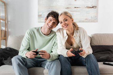 KYIV, UKRAINE - OCTOBER 24, 2022: cheerful young couple playing video game at home 