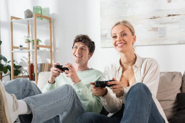 KYIV, UKRAINE - OCTOBER 24, 2022: joyful young couple holding joysticks while playing video game