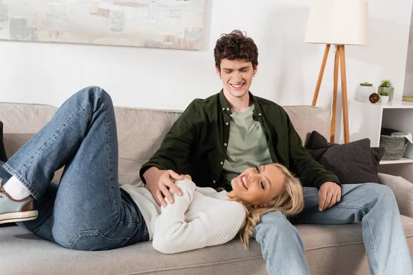 Happy Blonde Woman Lying Sofa Cheerful Boyfriend — Stockfoto