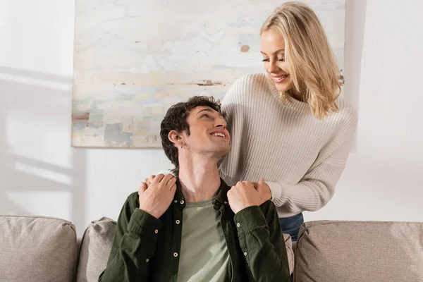 Young Cheerful Woman White Sweater Hugging Boyfriend Living Room — Stockfoto