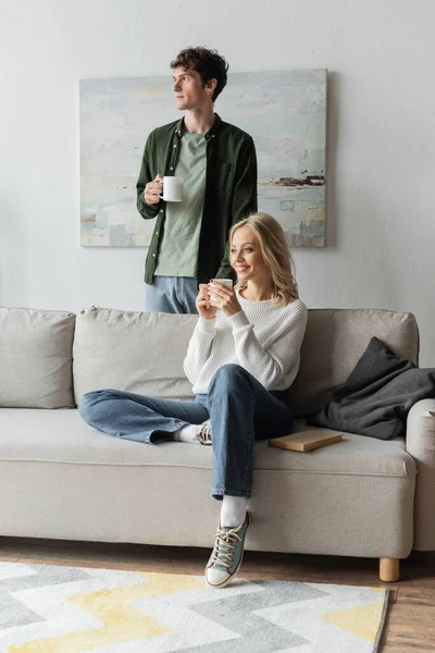 Curly Young Man Happy Blonde Woman Holding Cups Coffee Living — Foto de Stock