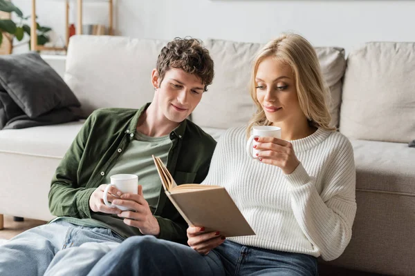 Blonde Woman Sweater Holding Cup Coffee Reading Book Boyfriend Living — Stockfoto