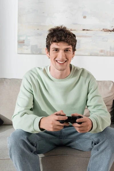 KYIV, UKRAINE - OCTOBER 24, 2022: cheerful young man in sweatshirt playing video game 