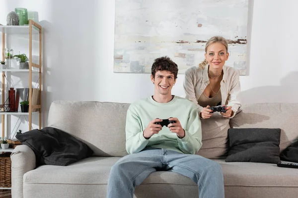 KYIV, UKRAINE - OCTOBER 24, 2022: smiling young couple playing video game at home 