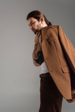 Stylish long haired model posing with jacket isolated on grey 