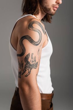 Cropped view of young man with tattoo standing isolated on grey 