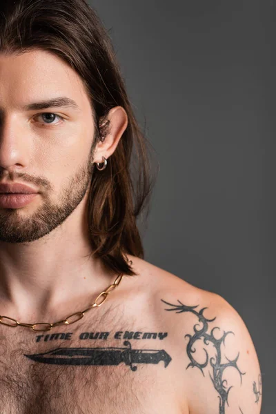 Cropped view of shirtless and tattooed model looking at camera isolated on grey