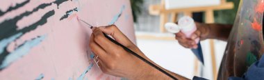 Afro-Amerikan ressamın atölyede, afişte tuvale resim yapması. 