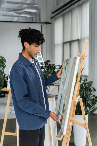 Side view of african american artist taking drawing from easel 