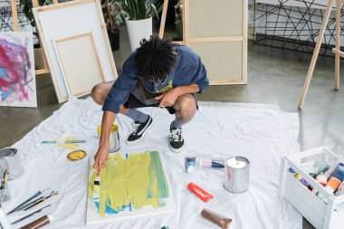 Sanat stüdyosunda Afrikalı Amerikalı ressam tuvale resim yapıyor. 