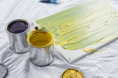 paints in buckets near canvas on cloth in studio  clipart