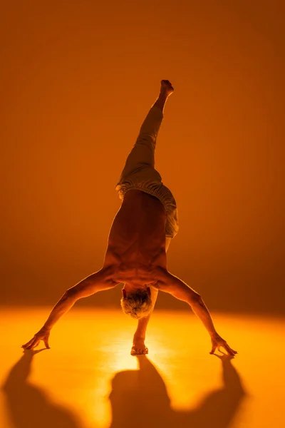 stock image full length of strong man practicing yoga on brown background 