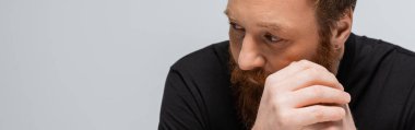 portrait of thoughtful bearded man with hands near face looking away isolated on grey, banner