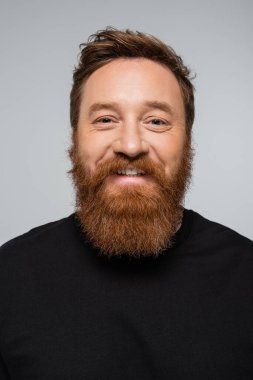 portrait of joyful man with beard smiling at camera isolated on grey