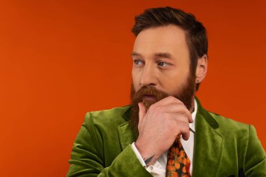 Portrait of bearded man in jacket looking away on red background 