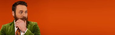 Bearded model in jacket looking away on red background, banner 