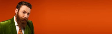 Focused and breaded man looking at camera on red background, banner 