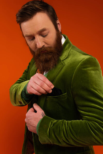 Portrait of tattooed model putting handkerchief in jacket pocket on red background 