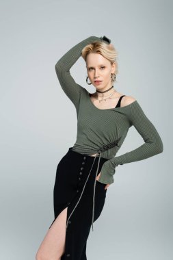 Sarışın, uzun kollu gömlekli, seksi etekli, elleri kalçasında gri renkte poz veren kadın. 