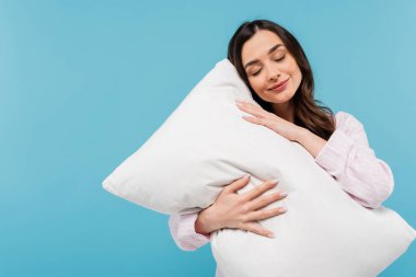 brunette young woman in pajamas sleeping on white pillow isolated on blue 