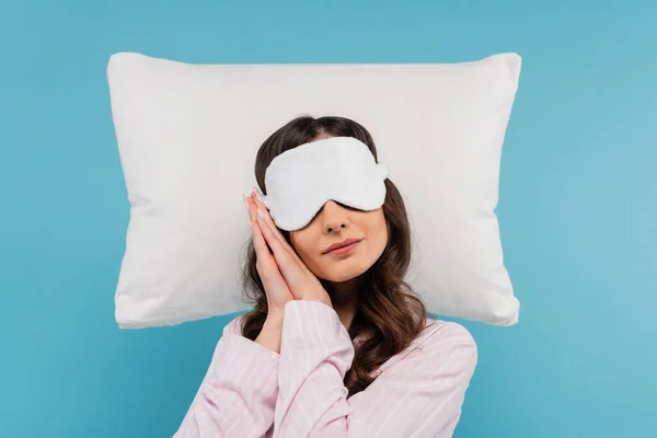 パジャマ姿の若い女性と青い枕の上に寝そべっているナイトマスク — ストック写真