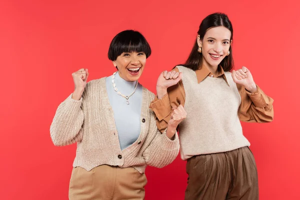 stock image excited asian mother and daughter in stylish clothes celebrating isolated on coral 