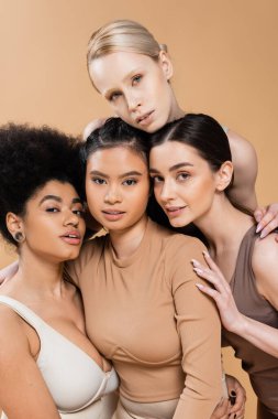 sensual multicultural models in underwear looking at camera isolated on beige
