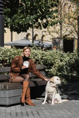 Deri ceketli, Asya yemeği ve labrador sarmaşığı taşıyan mutlu sarışın bir kadın. 