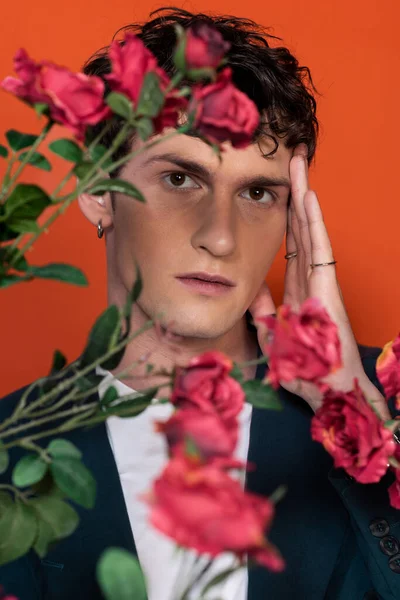 stock image Portrait of brunette model looking at camera near blurred flowers isolated on red 