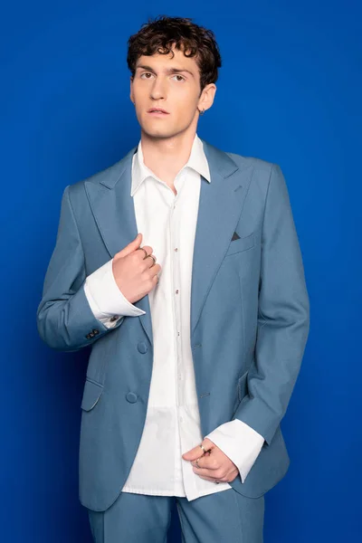 Fashionable man in shirt and suit posing on blue background