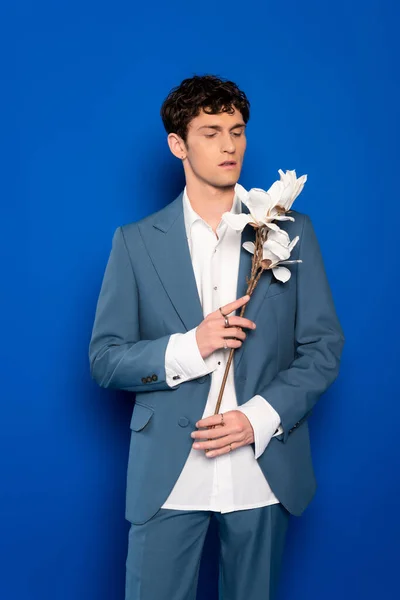Trendy Young Man Holding Magnolia Flowers Blue Background — Stock Photo, Image