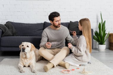 Baba ve Labrador 'un yanında otururken dudak parlatıcısı tutan kız. 