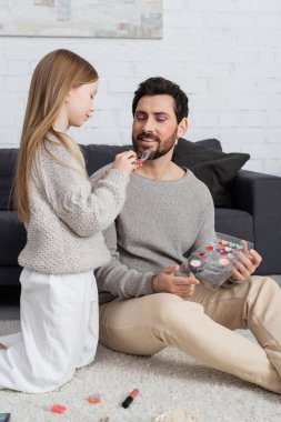 Mutlu baba, güzellik oyunu oynarken elinde far ürünü tutan ergen çocuğa bakıyor. 