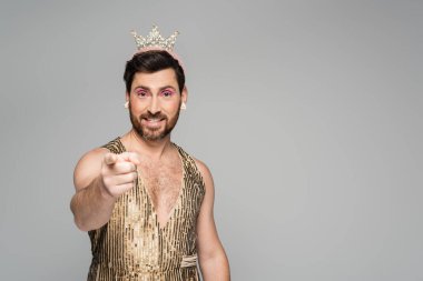 Kafasında oyuncak tacıyla neşeli bir adam ve gri parmağıyla prenses elbisesi. 