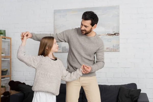 stock image smiling beaded man with preteen daughter holding hands while dancing at home