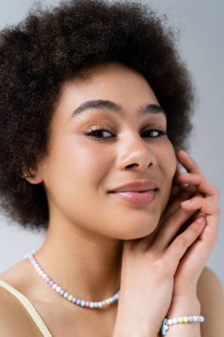 Aksesuarlı Afro-Amerikan kadın portresi Gri renkli kameraya bakıyor. 