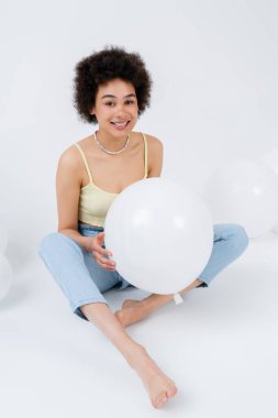 Neşeli Afrikalı Amerikalı kadın gri arka planda balon tutuyor. 