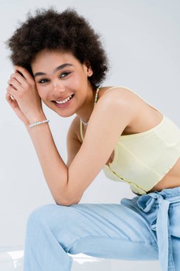 Gri koltuğa yakın poz veren pozitif Afro-Amerikan modeli 