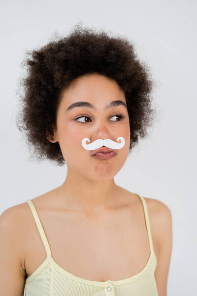 Portrait of african american woman with paper moustache pouting lips isolated on grey 