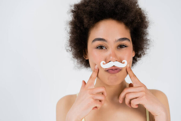 African american woman with paper moustache looking at camera isolated on grey 