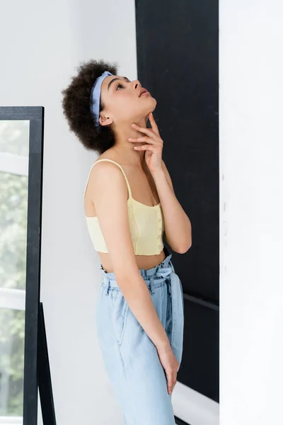 Afroamerikanerin Mit Stirnband Berührt Hals Der Nähe Spiegel Auf Grauem — Stockfoto