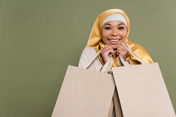 Retrato Mulher Multirracial Positiva Hijab Segurando Sacos Compras Isolados Verde — Fotografia de Stock