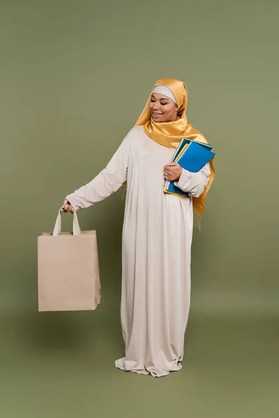 Estudante Multirracial Despreocupado Hijab Segurando Sacos Compras Cadernos Fundo Verde — Fotografia de Stock