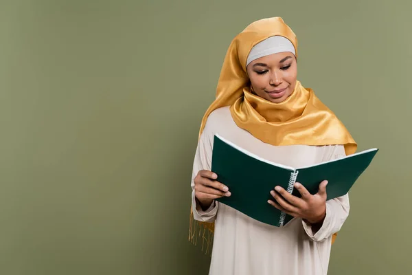 多种族穆斯林学生在绿色背景下看笔记本 — 图库照片