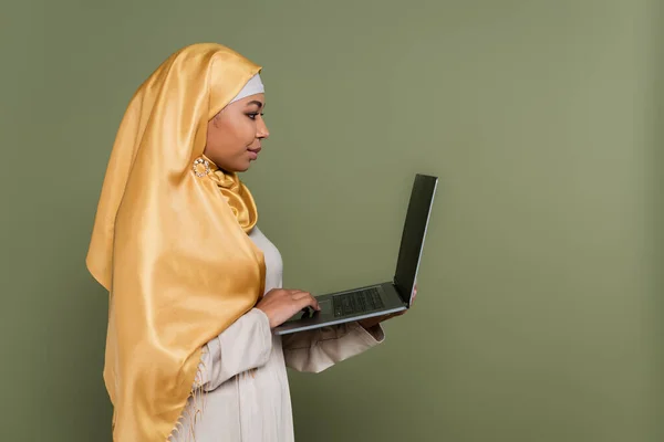 用绿色笔记本电脑隔离的多种族穆斯林自由职业者侧视图 — 图库照片