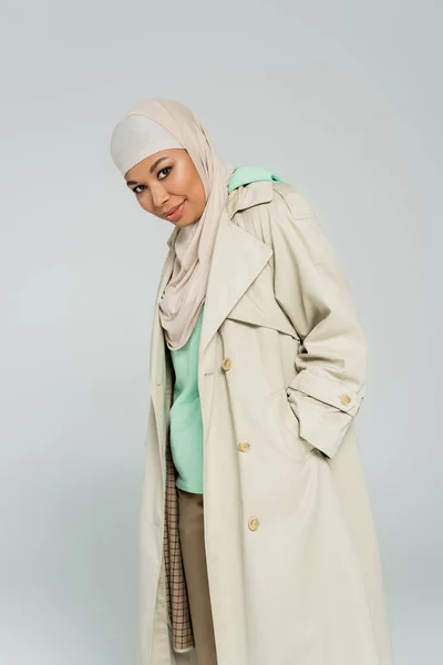 Erfreut Multirassische Frau Hijab Und Trenchcoat Stehend Mit Der Hand — Stockfoto
