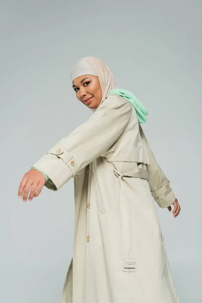 히잡을 여성이며 회색에 고립된 포즈를 취하며 카메라 앞에서 코트를 — 스톡 사진