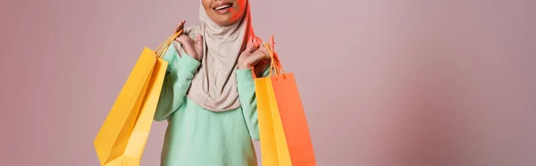 Обрезанный Вид Счастливой Многорасовой Мусульманки Держащей Желтые Пакеты Покупок Розово — стоковое фото