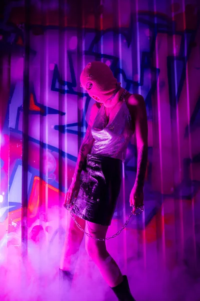 穿着巴拉克拉瓦的性感女人 头戴闪亮的上衣 穿着皮裙 脚上挂着一条带着紫色浓烟的彩色铁链的涂鸦 — 图库照片