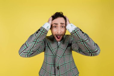 Screaming man in jacket covering ears isolated on yellow   clipart